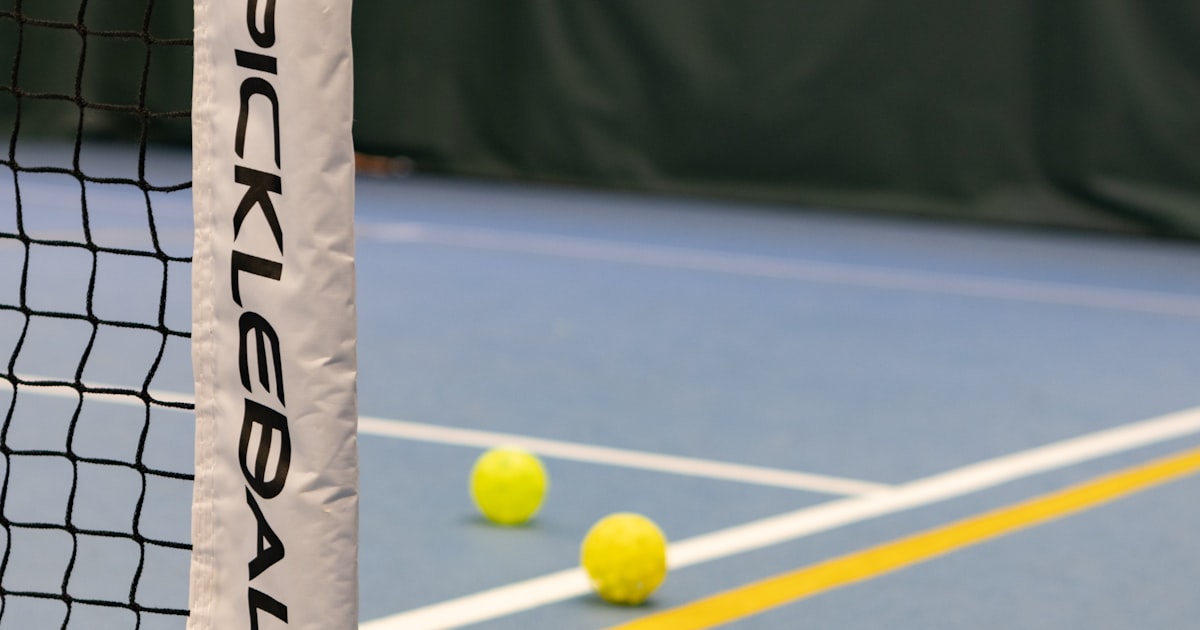 Three pickleball balls on a court near the net