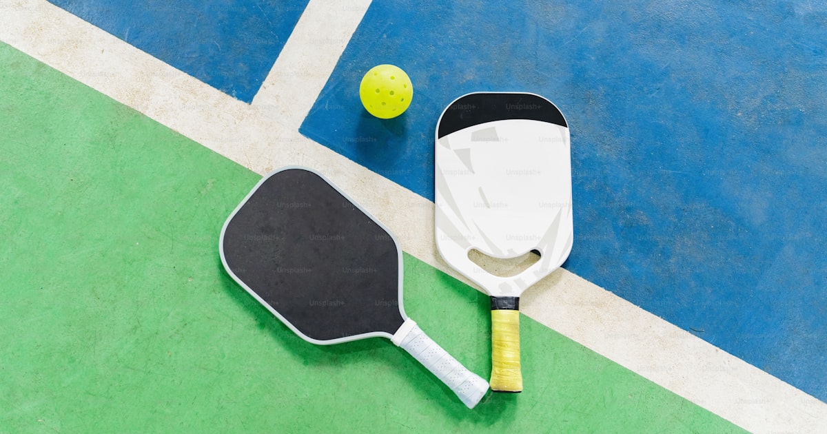 Two pickleball paddles and a ball arranged on a court