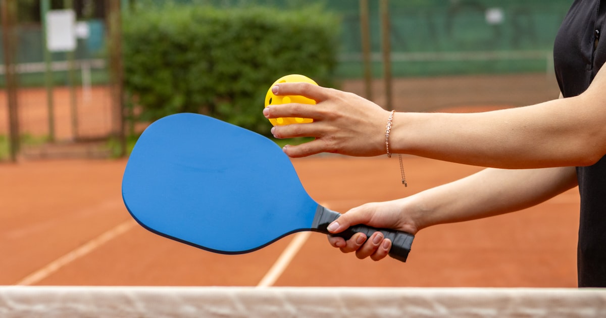 A player holding a pickleball paddle and ball