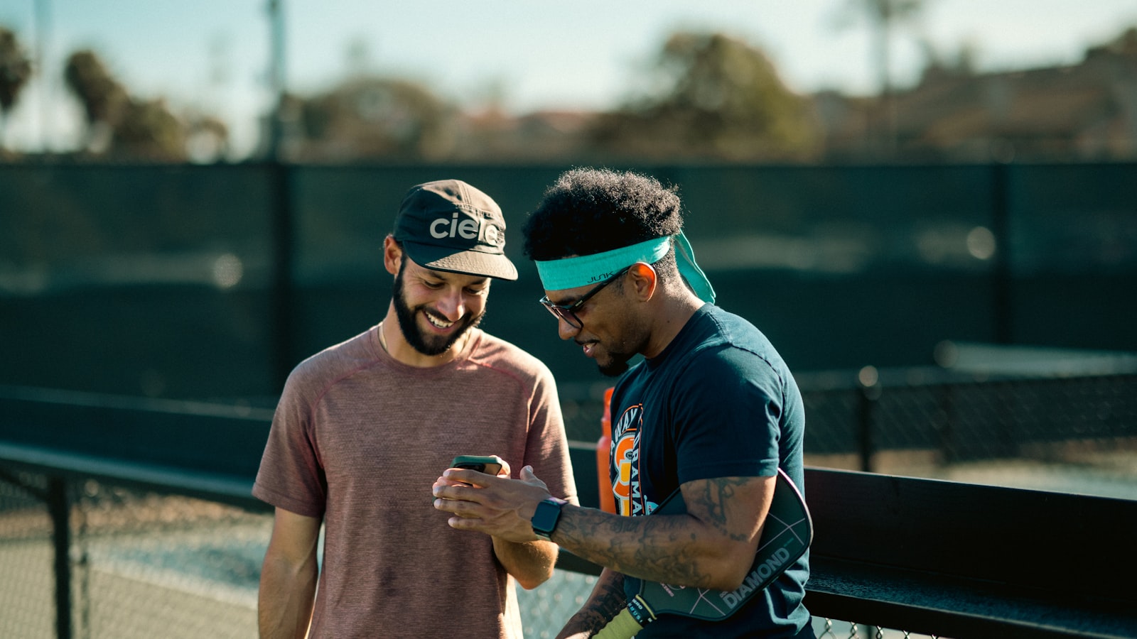 Two players standing together on a pickleball court, paddles in hand, mid-conversation before a game
