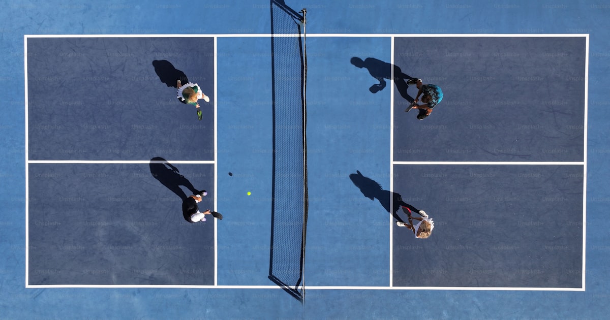 Three players standing on a pickleball court holding paddles