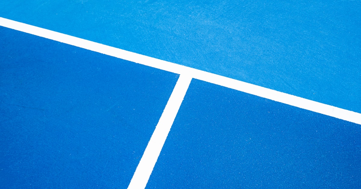 A blue pickleball court with white line markings