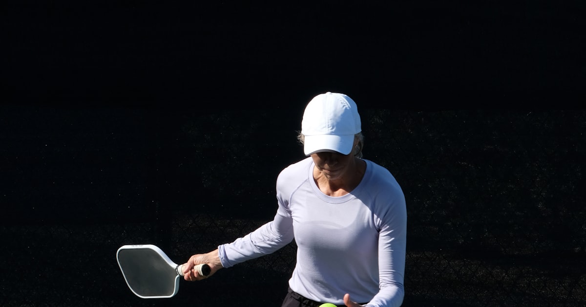 A player in a compact, low stance softly redirecting the ball off her paddle