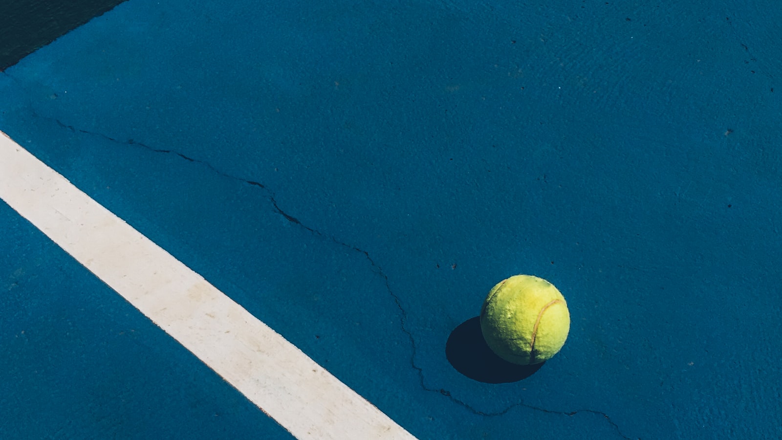 A yellow ball resting on a hard court surface